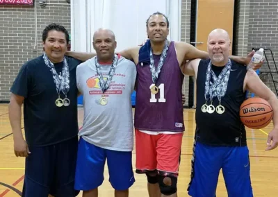 Basketball players posing with medals indoors