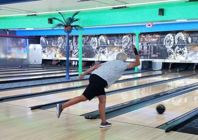 Senior athlete releasing bowling ball on indoor lane