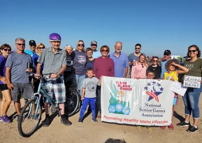 Senior cycling group posing with Idaho Senior Games banner outdoors