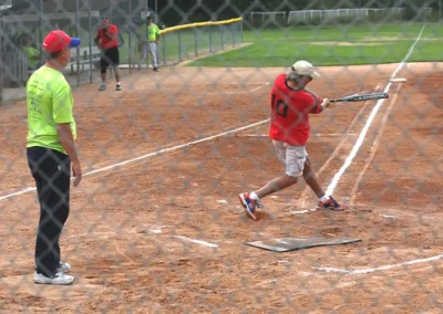 Senior softball player swinging bat during game